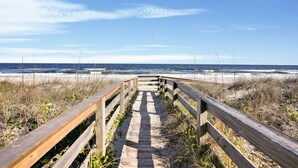 A wooden boardwalk leading to a beach with a clear sky.