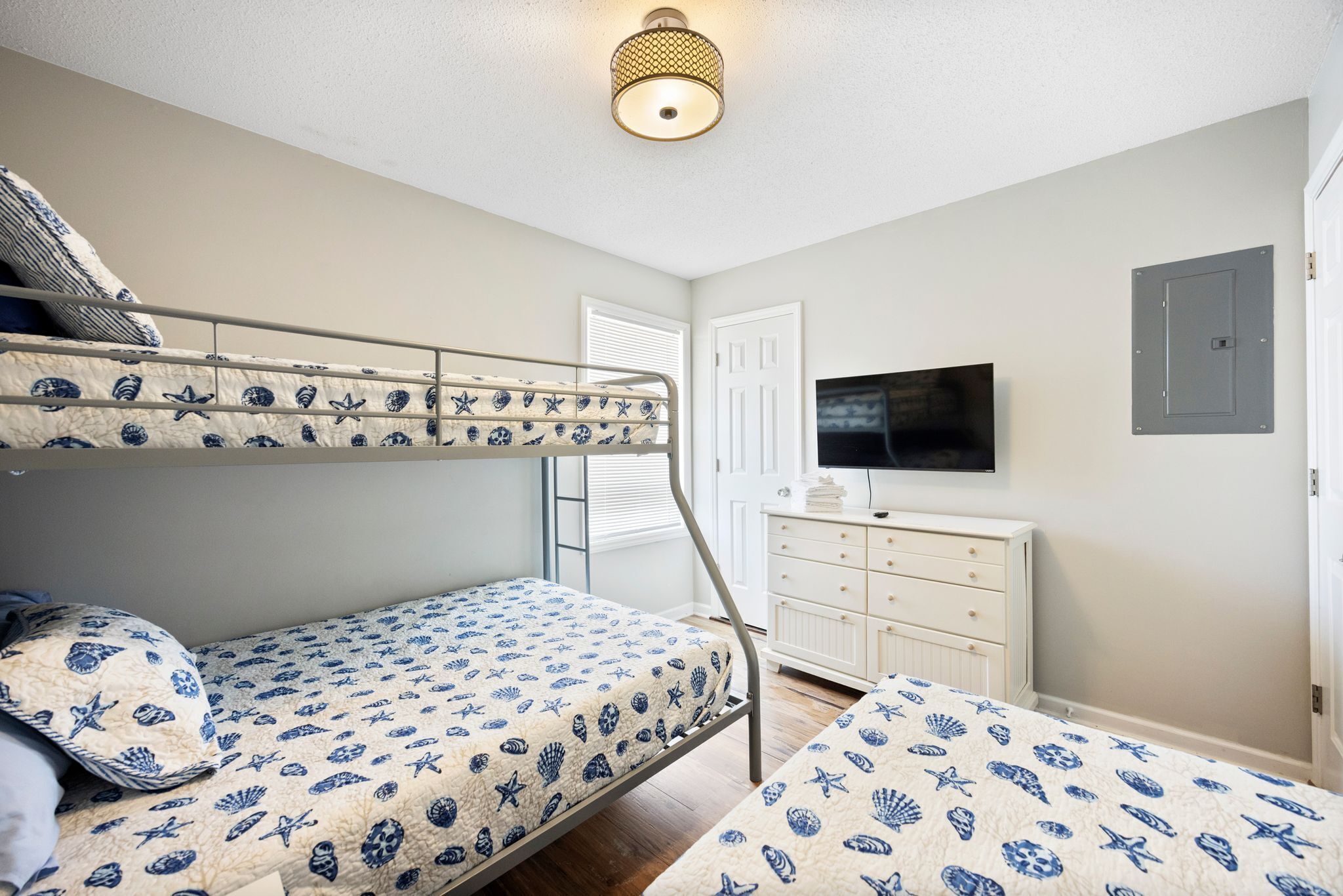 A bunk bed room with a television and a dresser.