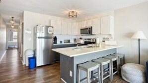 A modern kitchen with white cabinets, stainless steel appliances, and a central island with bar stools.