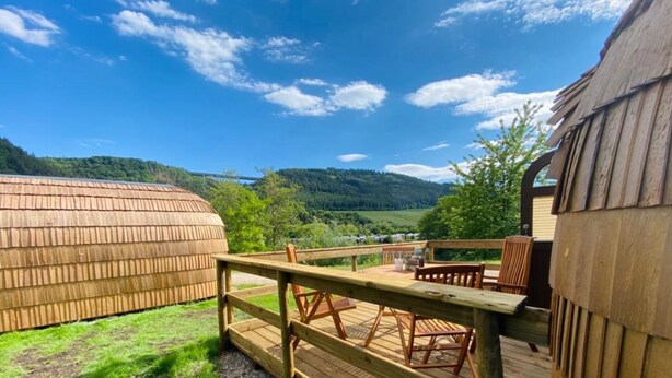 Una terraza de madera con vistas a un valle y colinas.