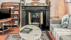 Un soggiorno con camino, televisione, libreria e tappeto decorato.