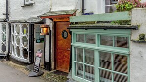 Un pub tradizionale con una porta in legno con l'insegna "Laity", una targa e una finestra con persiane.