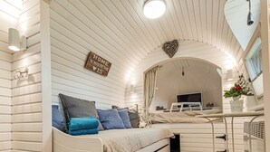 Un interior de cabaña acogedor con una cama, un escritorio y una televisión.