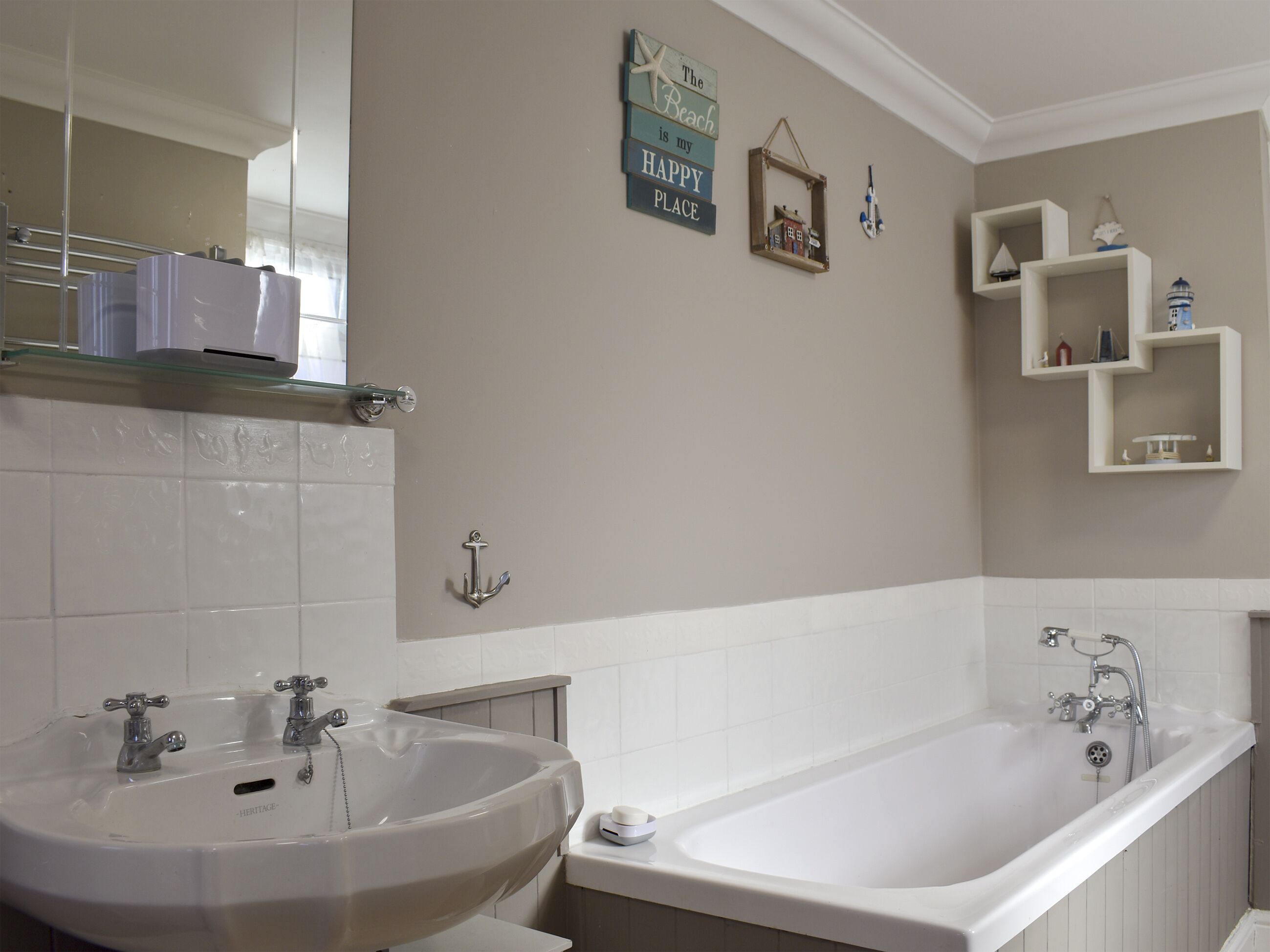 Un baño con lavamanos doble, bañera y tocador con repisas.
