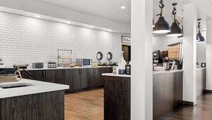 Una cocina moderna con salpicadero de ladrillo blanco, armarios de madera oscura y una isla central.
