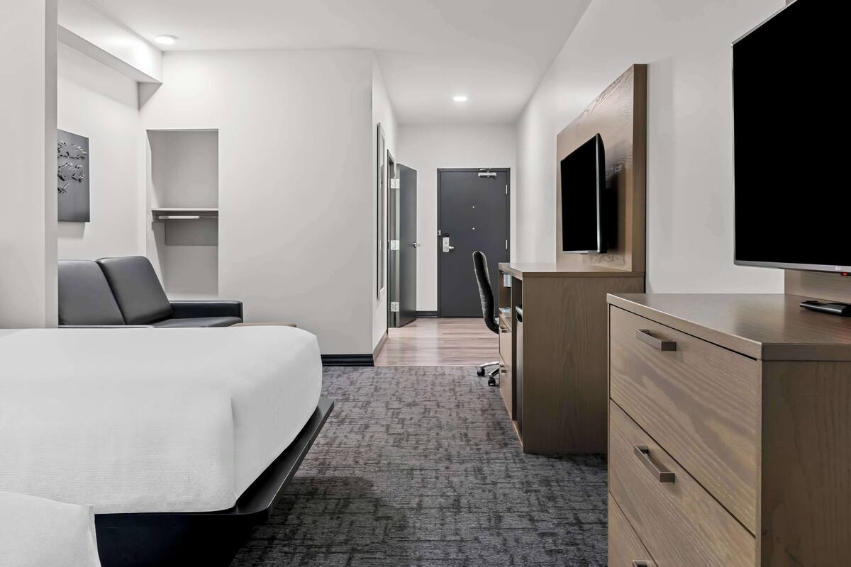 A hotel room with a bed, a desk, a chair, a television, and a wardrobe.