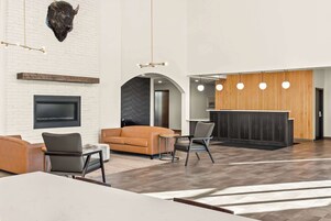 Un vestíbulo moderno con chimenea, zona de estar y mostrador de recepción.