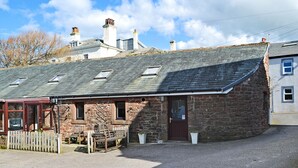 A stone cottage with a sloped roof, a wooden door, and a gravel driveway. - 1 bedroom accommodation in St Bees, near Whitehaven (St Bees, near Whitehaven)