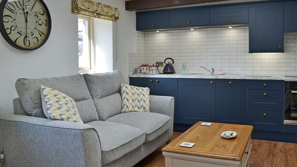 A modern kitchen with blue cabinets, a white tiled backsplash, and a wooden coffee table. - 1 bedroom accommodation in St Bees, near Whitehaven (St Bees, near Whitehaven)