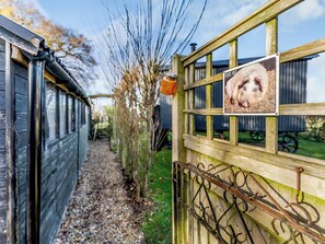 A wooden gate with a sign, a gravel path, and a wooden structure in the background. - 1 bedroom accommodation in Hassocks (Hassocks)