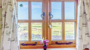 A double wooden door with glass panels, flanked by curtains with animal prints, leading to a window with a view of a green landscape. - 1 bedroom accommodation in Hassocks (Hassocks)