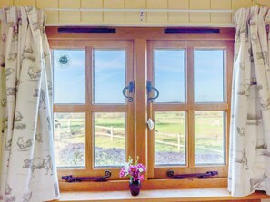 A double wooden door with glass panels, flanked by curtains with animal prints, leading to a window with a view of a green landscape. - 1 bedroom accommodation in Hassocks (Hassocks)