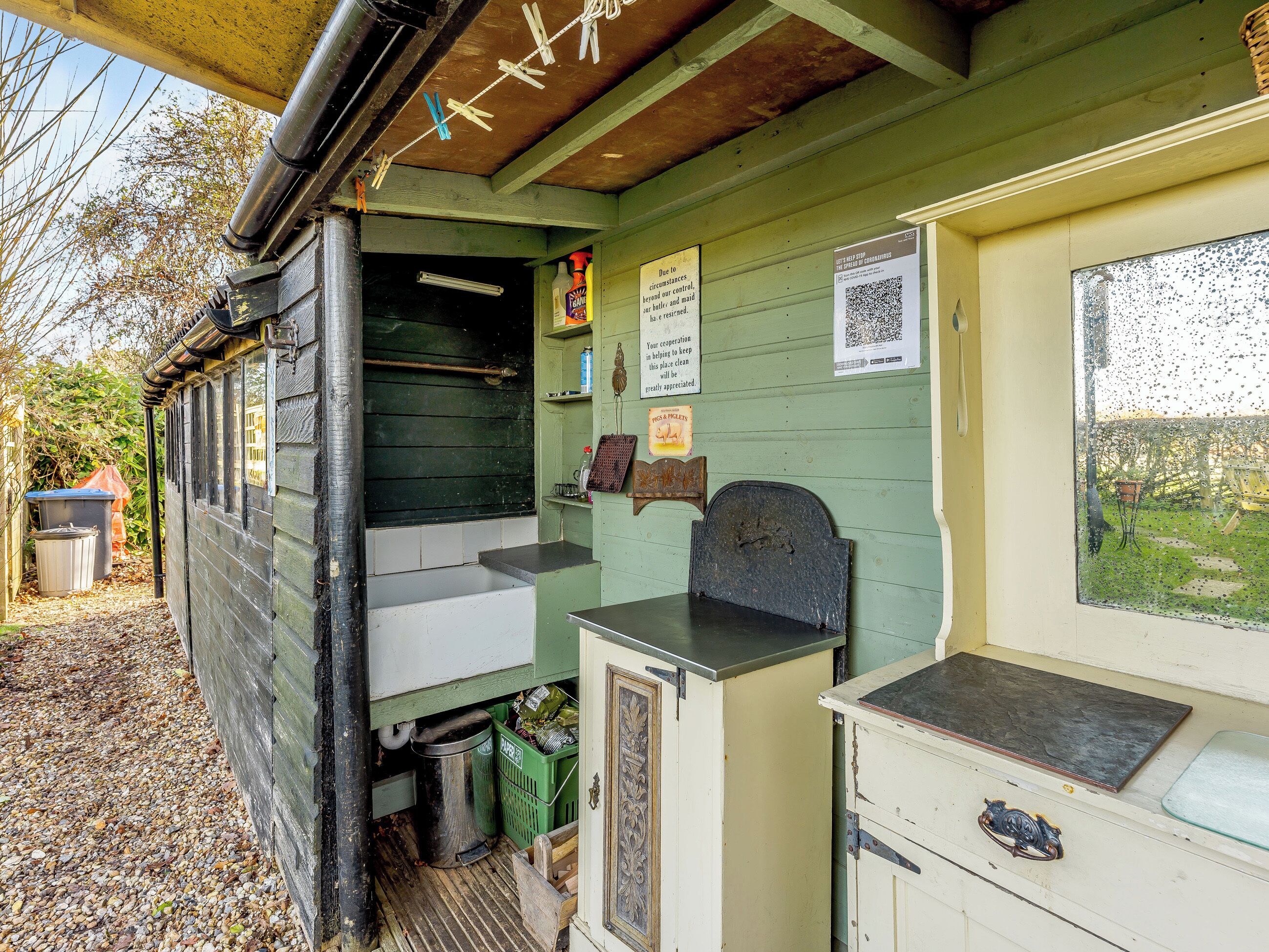 Une structure rustique en bois, dotée d’un comptoir, d’une poubelle et d’une fenêtre donnant sur l’extérieur.