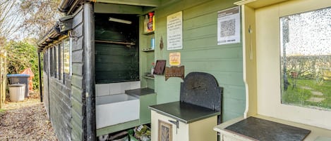 A rustic wooden structure with a counter, a trash bin, and a window with a view of the outdoors.