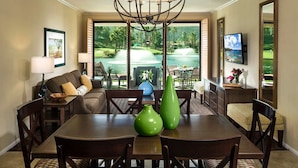 A dining area with a large table, chairs, and a chandelier. There is a view of a pool and greenery outside the windows. - Christmas Welk San Diego California 2 bedroom Lock Off (San Diego)