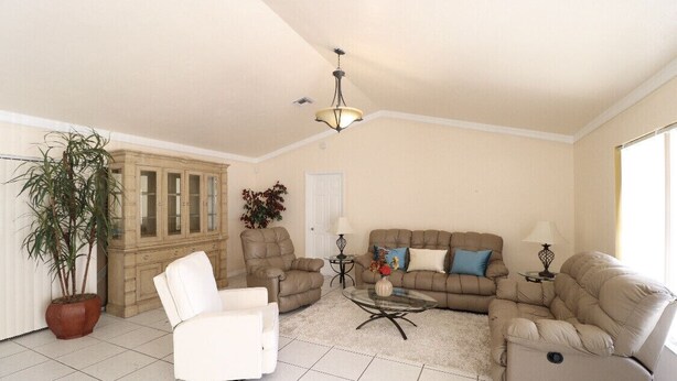 A living room with beige walls, a chandelier, a sofa set, a white armchair, a coffee table, and a potted plant. - Family home , canal view, 10 min a way from Naples pier (Naples)