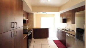 A modern kitchen with wooden cabinets, stainless steel appliances, and a red rug. - Family home , canal view, 10 min a way from Naples pier (Naples)
