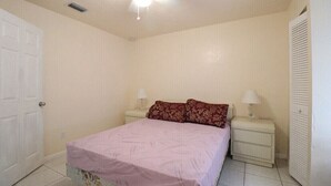 A bedroom with a bed, two bedside tables, a ceiling fan, and a door. - Family home , canal view, 10 min a way from Naples pier (Naples)