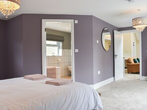 A bedroom with a bed, a bathroom with a toilet and sink, and a hallway leading to a living area. - The Cottage at Stainsacre Hall (Stainsacre, near Whitby)