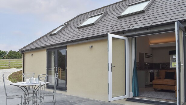 A house with a patio, a sliding glass door leading to an interior with a kitchen and a living area.