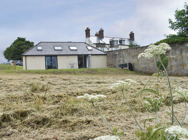 A building with a flat roof, a small attached structure, and a stone wall. - The Cottage at Stainsacre Hall (Stainsacre, near Whitby)