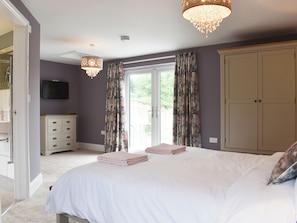 A bedroom with a bed, a dresser, a television, and a wardrobe.