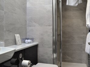 Une salle de bain avec une douche à parois de verre, un lavabo blanc et un porte-rouleau de papier toilette.