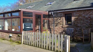 A stone building with a wooden fence, a small garden, and a wooden bench. - The Milking Parlour - UK30866 (St Bees, near Whitehaven)