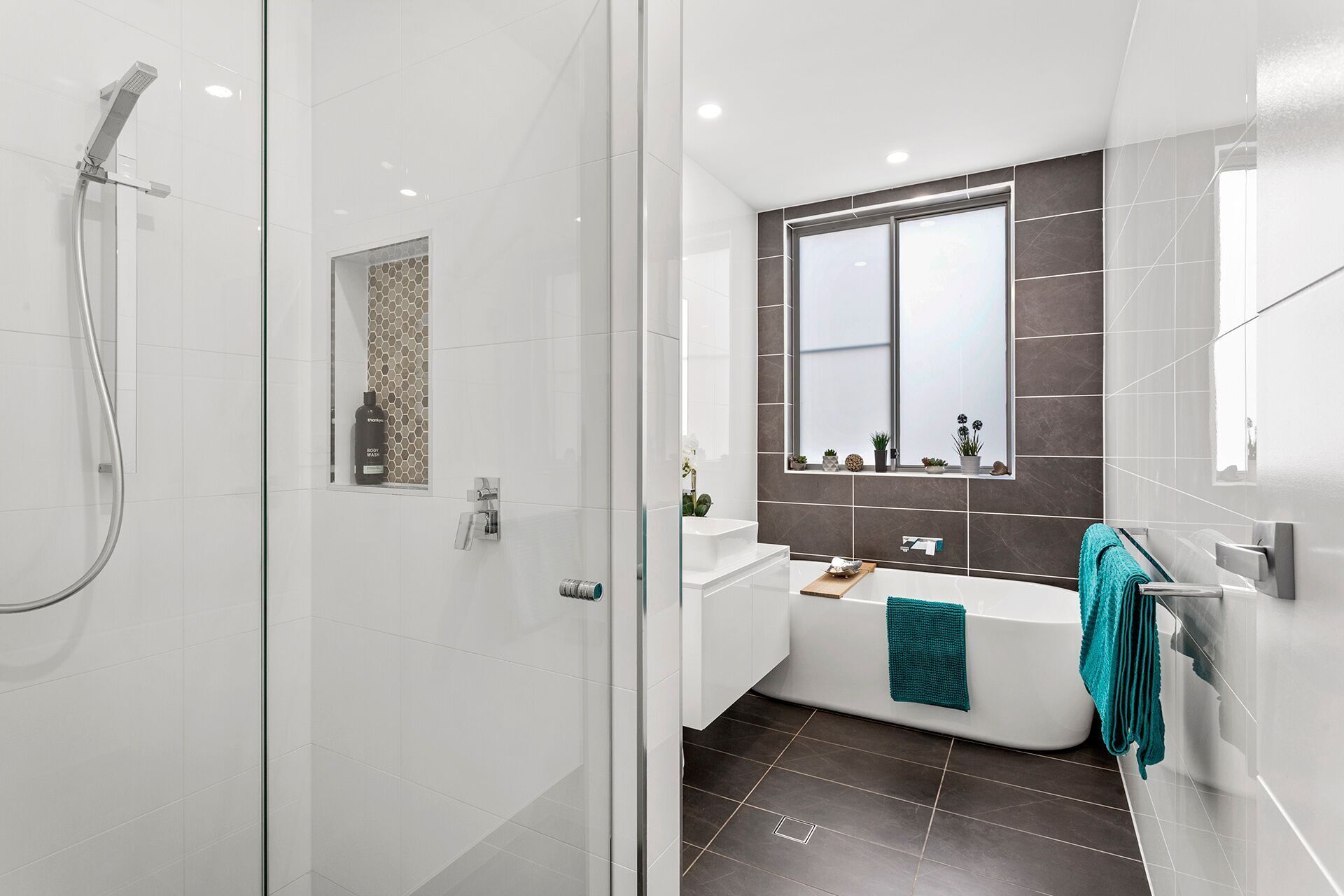 Un bagno moderno con cabina doccia in vetro, una vasca freestanding e uno specchio grande sopra il lavabo.