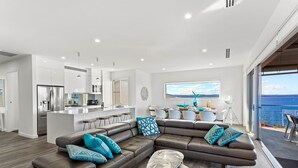 Un espacio moderno para vivir con un amplio sofá seccional en forma de L, una zona de cocina y una mesa de comedor.