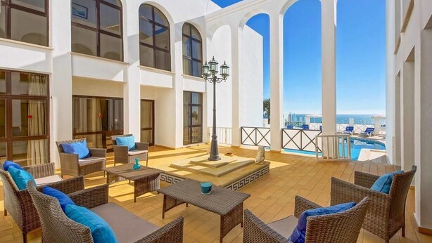 Une vaste terrasse extérieure, dotée de meubles en osier et offrant une vue sur la mer.