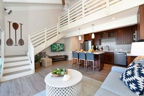 A spacious living area with a staircase, a kitchen with modern appliances, and a comfortable seating area. - Relaxing Getaway OceanFront 2BD wPool AC - Hoyochi Nikko 201 (Lahaina)
