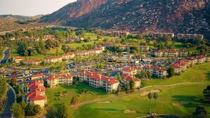 A resort with multiple buildings, a golf course, and mountainous terrain in the background.