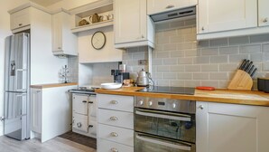 A modern kitchen with white cabinetry, a built-in oven, and a coffee machine. - A lovely three bedroom home, perfect for friends and family alike. (Bridstow, near Ross-on-Wye)