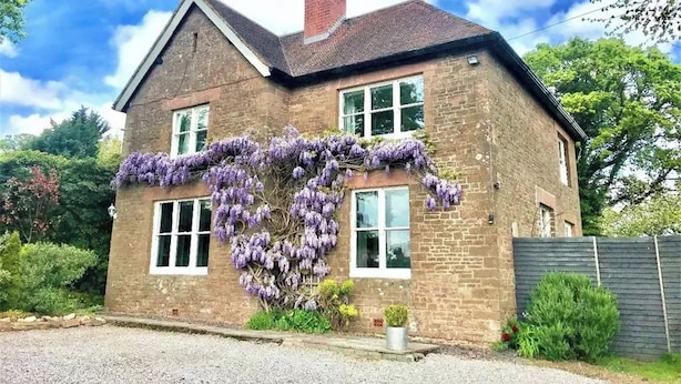 A two-story brick house with a prominent ivy-covered front wall and a visible chimney. - A lovely three bedroom home, perfect for friends and family alike. (Bridstow, near Ross-on-Wye)