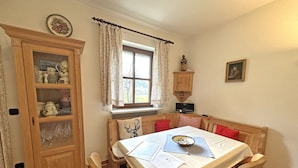 Zona pranzo con tavolo in legno, sedie e mobiletto con ante in vetro.