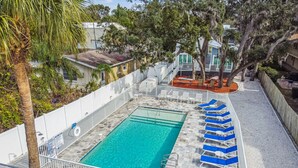 A rectangular pool with clear blue water, surrounded by a white fence and blue lounge chairs. - Dunedin Cottage on Pinellas Trail w/ Heated Pool, Walk or Bike to Downtown Dunedin! (Dunedin)
