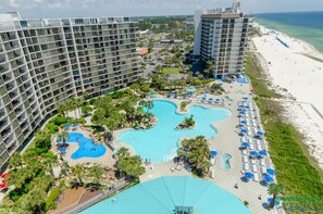Un hôtel composé de plusieurs immeubles de grande hauteur, doté d’un vaste espace piscine agrémenté de diverses installations aquatiques, et situé à proximité d’une plage.
