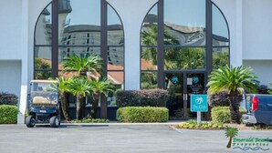 A building with large arched windows, a golf cart, and a sign for 'The Club'.