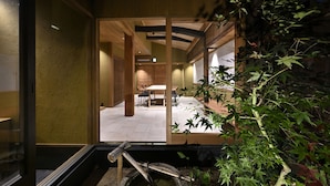 Un intérieur japonais traditionnel avec des portes coulissantes, un coin repas et un petit élément décoratif aquatique.