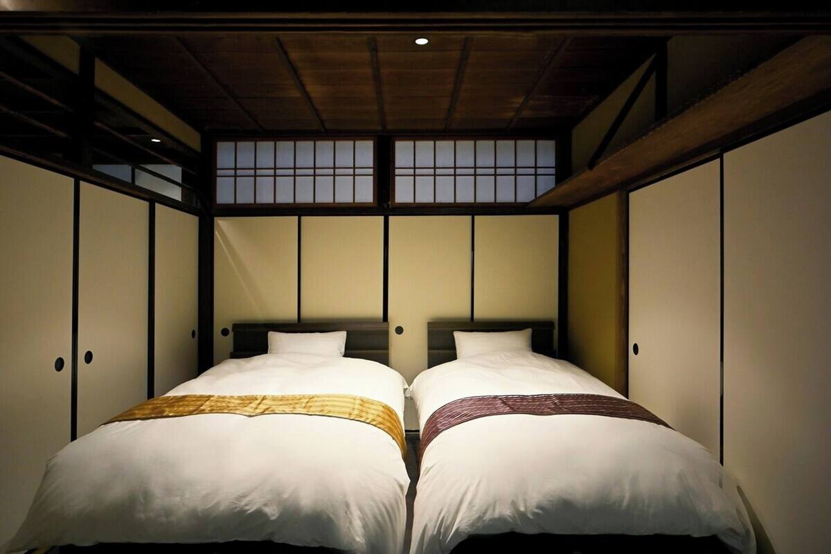 Une chambre avec deux lits, un lambris en bois et un plafond en pente agrémenté d’un puits de lumière.