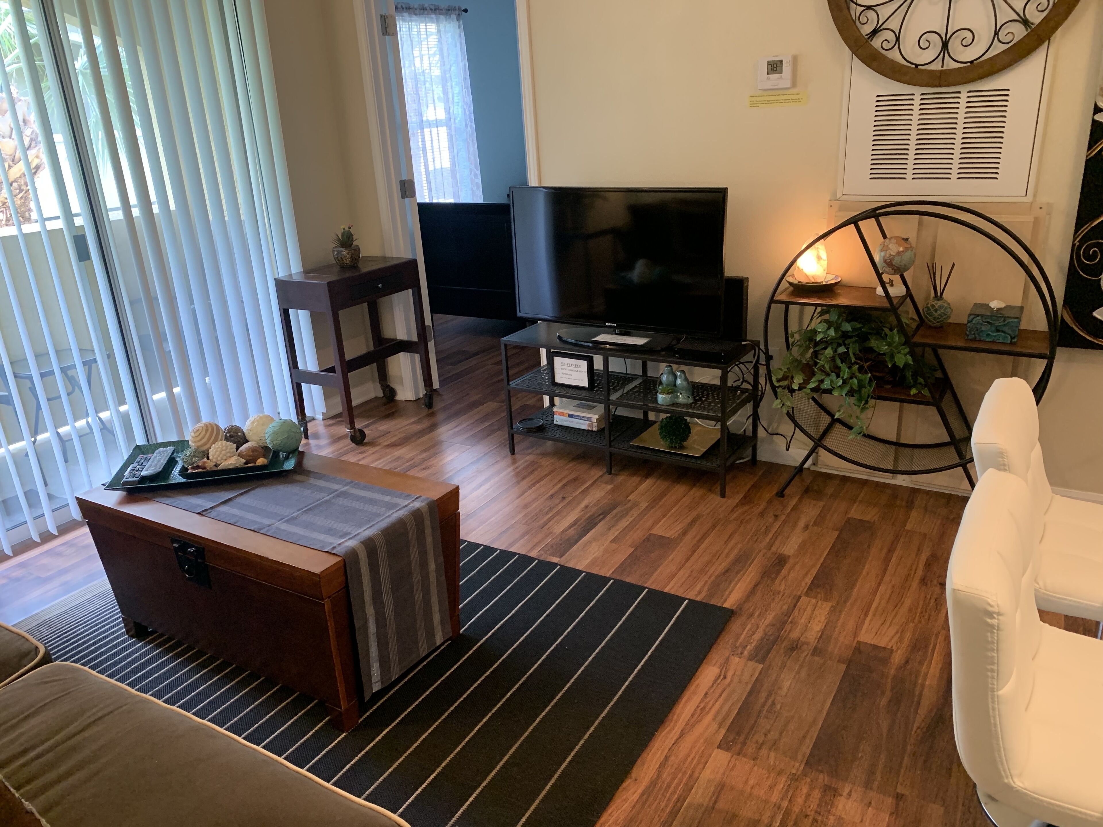 A living room with a TV, a coffee table, a sofa, and a small plant.