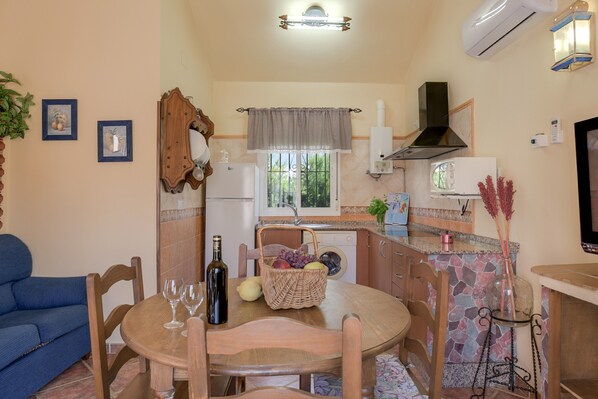 A compact kitchen with a dining table, chairs, a sink, and a stove.