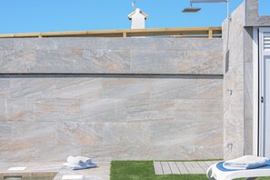 Un mur de pierre, une petite pelouse et une porte blanche.