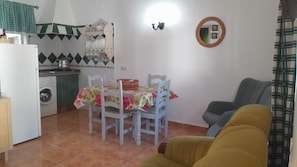 A compact kitchen with a washing machine, a dining table with chairs, and a sofa. - Beautiful Accommodation "Casa Clavel" with Private Pool, Air Conditioning and Terrace (Conil de la Frontera)