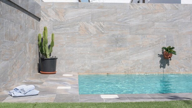 A swimming pool with a tiled wall, a cactus, and a potted plant. - Beautiful Accommodation "Casa Clavel" with Private Pool, Air Conditioning and Terrace (Conil de la Frontera)