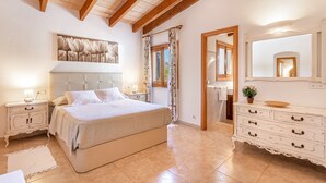 A bedroom with a bed, nightstands, a dresser, a mirror, and a headboard with a floral design. - Rural Country House with Pool, Wi-Fi, Lawn and Veranda (POLLENSA)