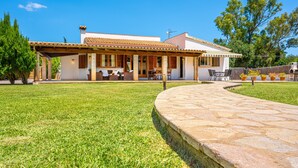 A house with a covered patio, a stone pathway, and a well-maintained lawn. - Rural Country House with Pool, Wi-Fi, Lawn and Veranda (POLLENSA)