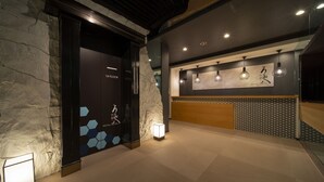 A hotel lobby with a reception desk, a stone wall, and a patterned wall.