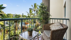 A balcony with wicker furniture, a glass table, and potted plants. - Family & Pet Friendly- Long Stays Welcome! (Bilinga)